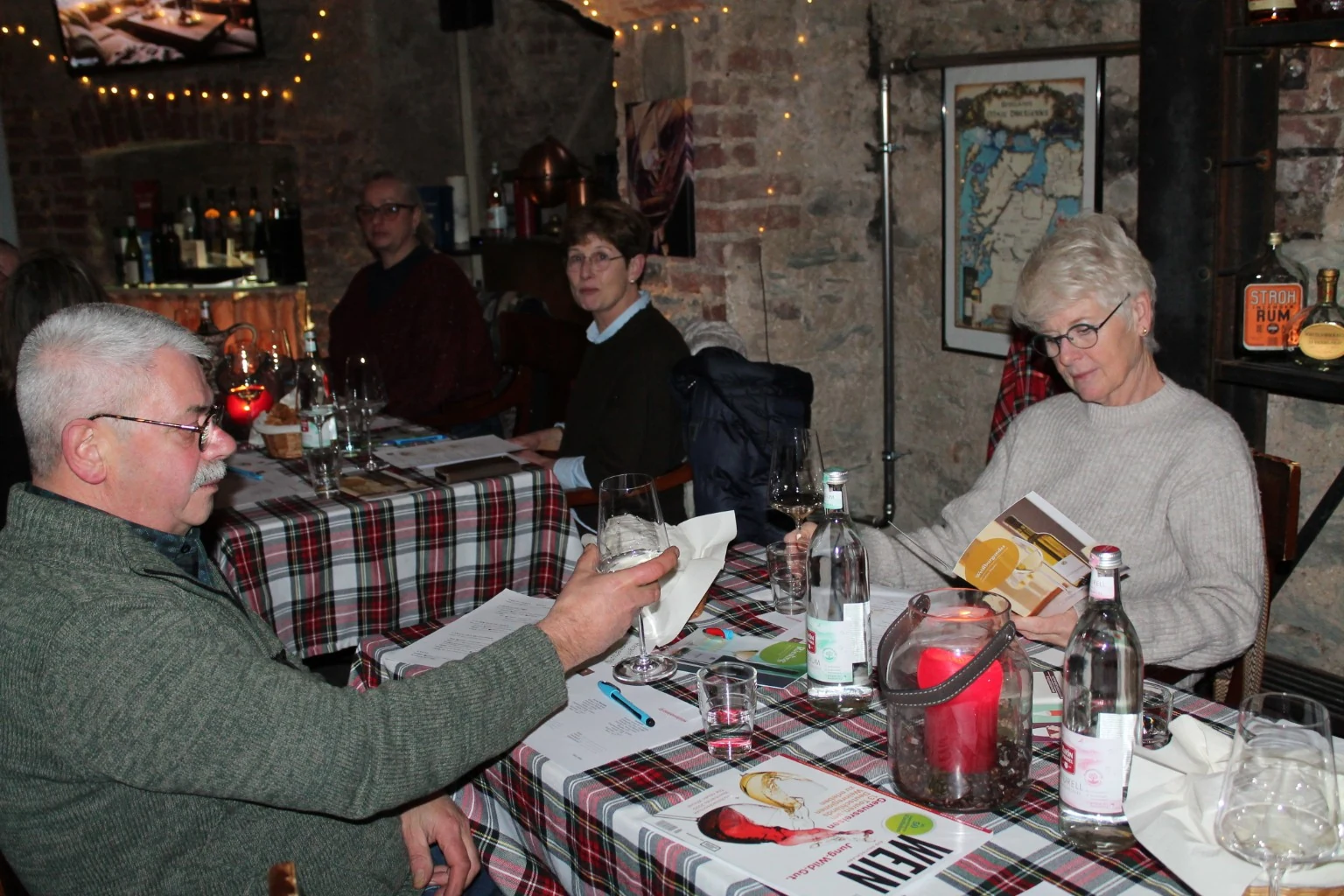 Gäste bei einer Weinprobe mit Unterlagen und Gläsern